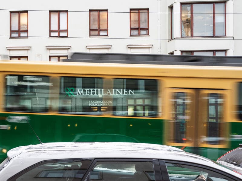 Helsingissä kulkeva ratikka, jonka kyljessä on Mehiläisen mainos.