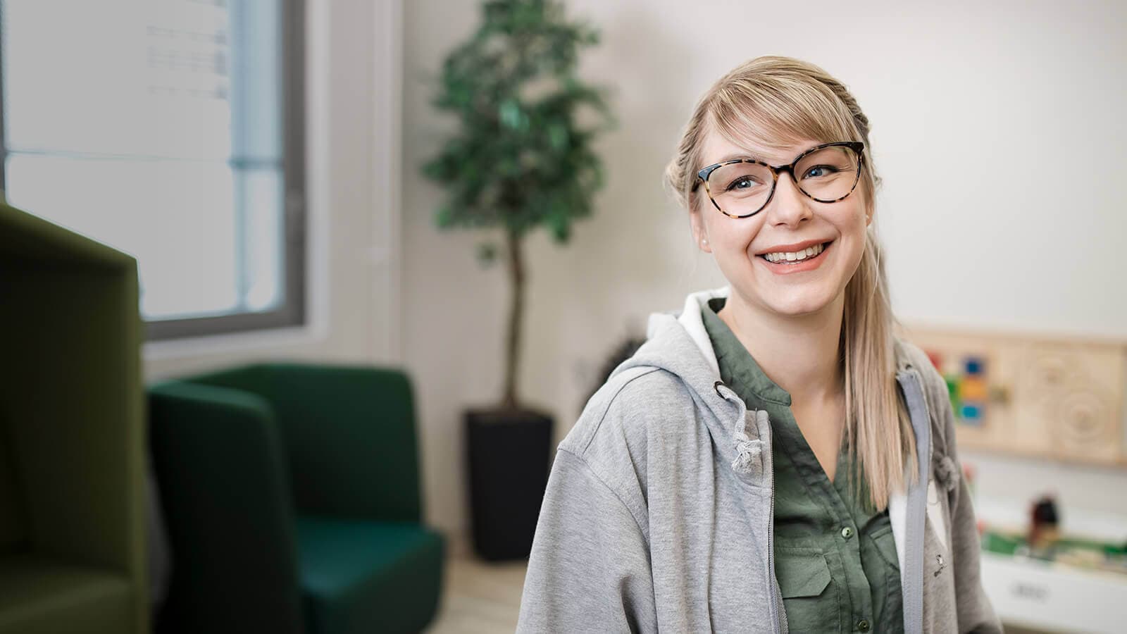 Vaaleahiuksinen nainen hymyilee kasvoillaan silmälasit ja työskentelee Mehiläisen asiakaspalvelijana auttaen ajan perumisessa.