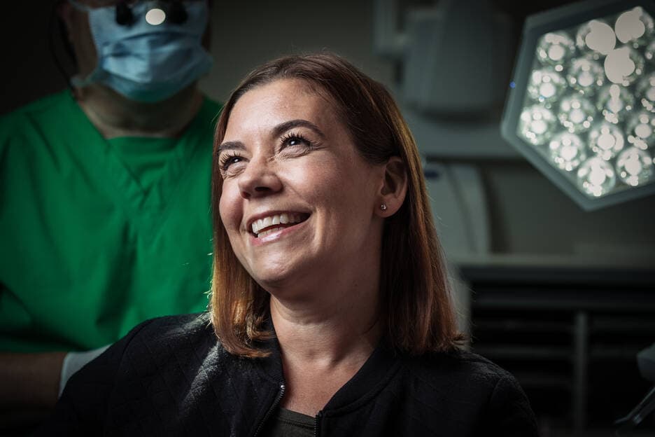A woman smiles happily at the dentist.