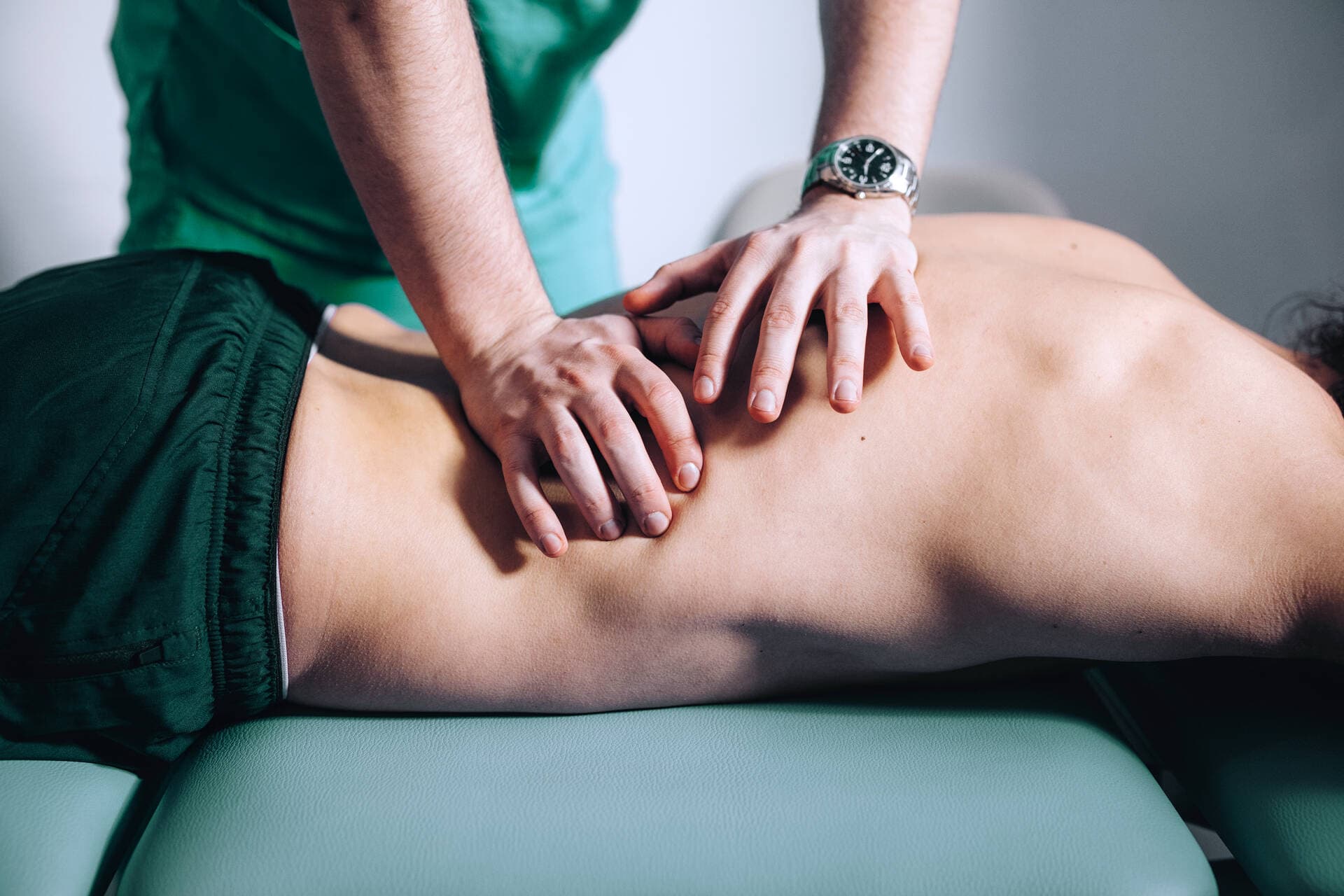 Henkilö on osteopatiakäsittelyssä vatsallaan.