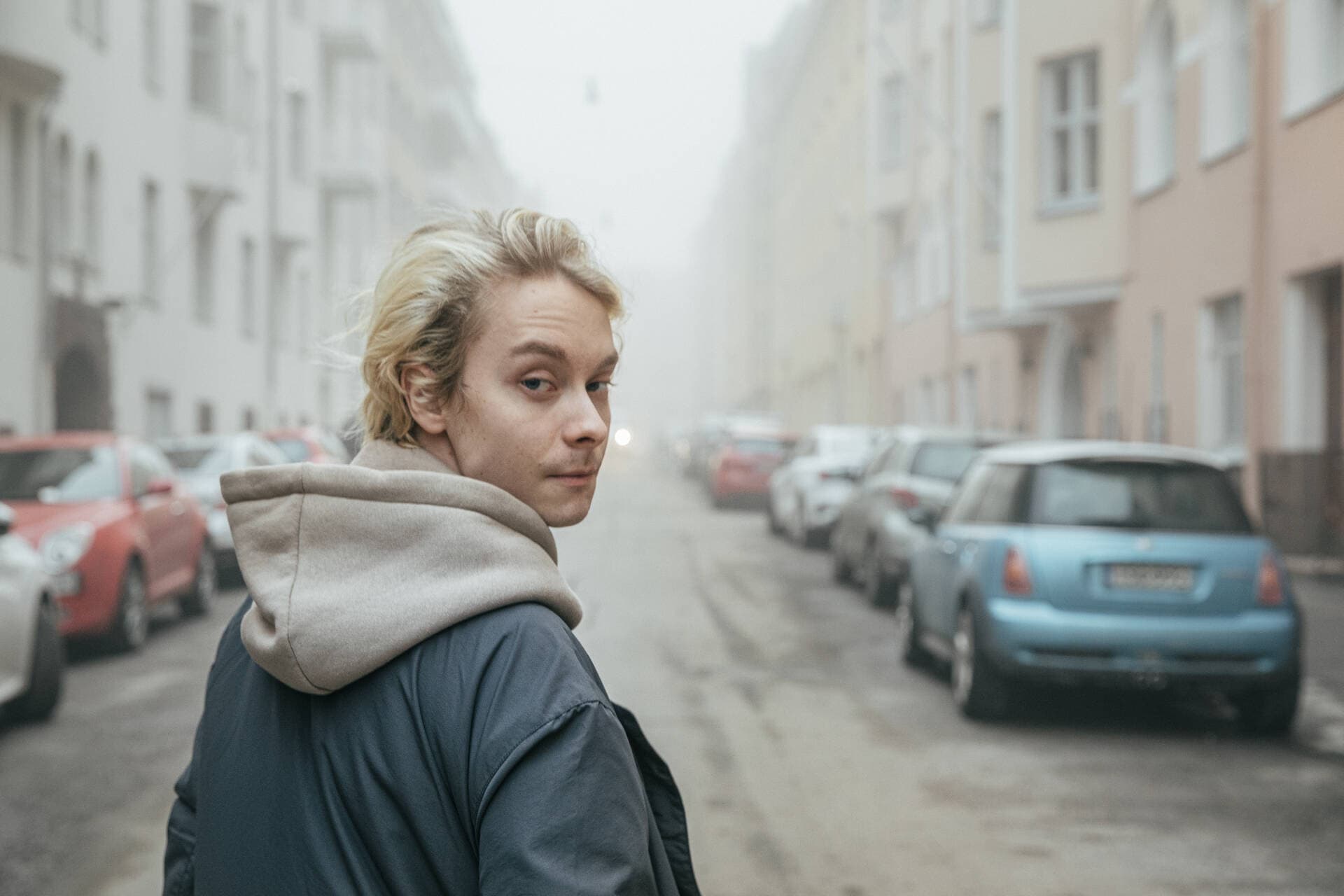 Poika kävelee keskellä sumuista katua.