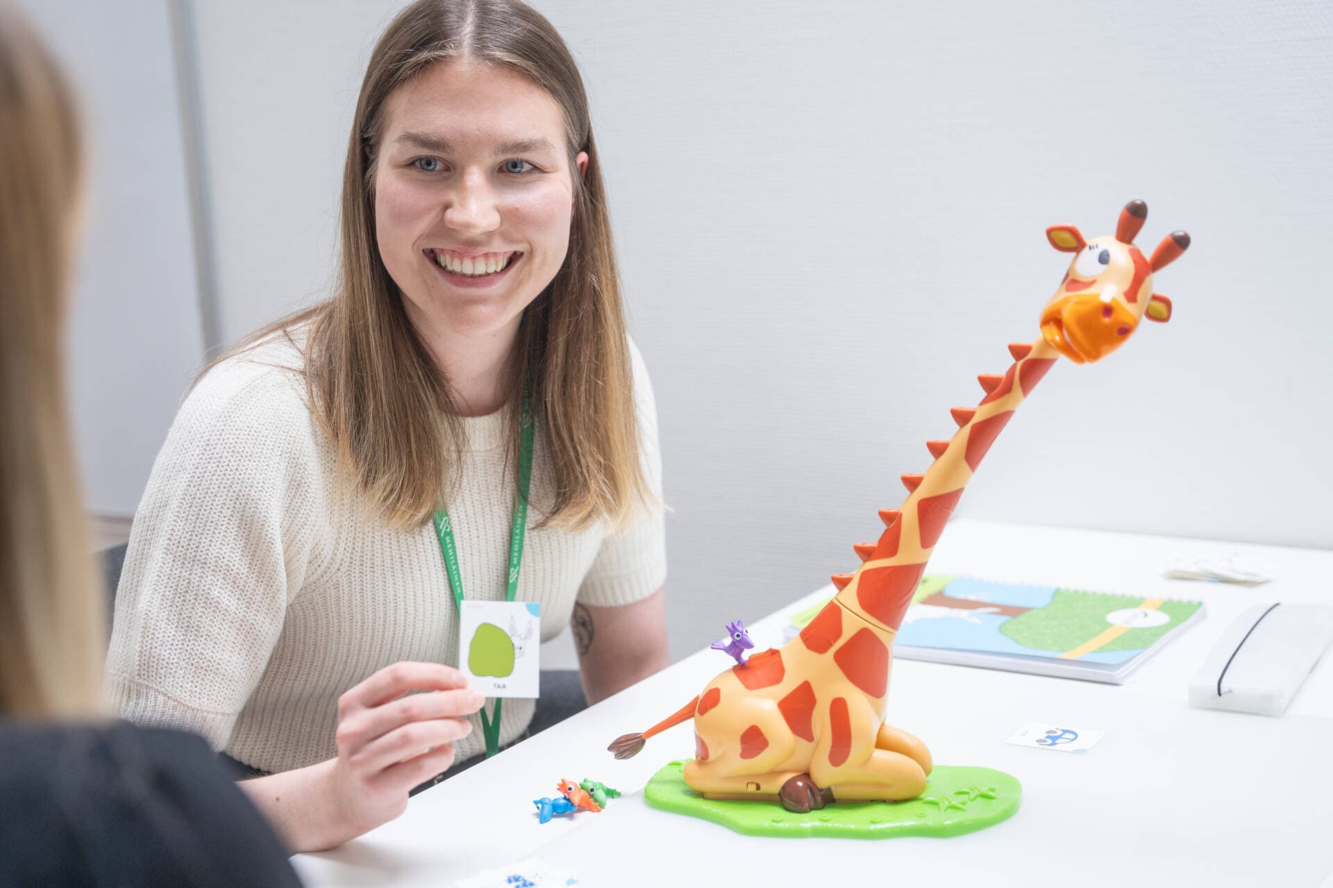 Puheterapeutti esittelee kortteja asiakkaalle hymyillen.