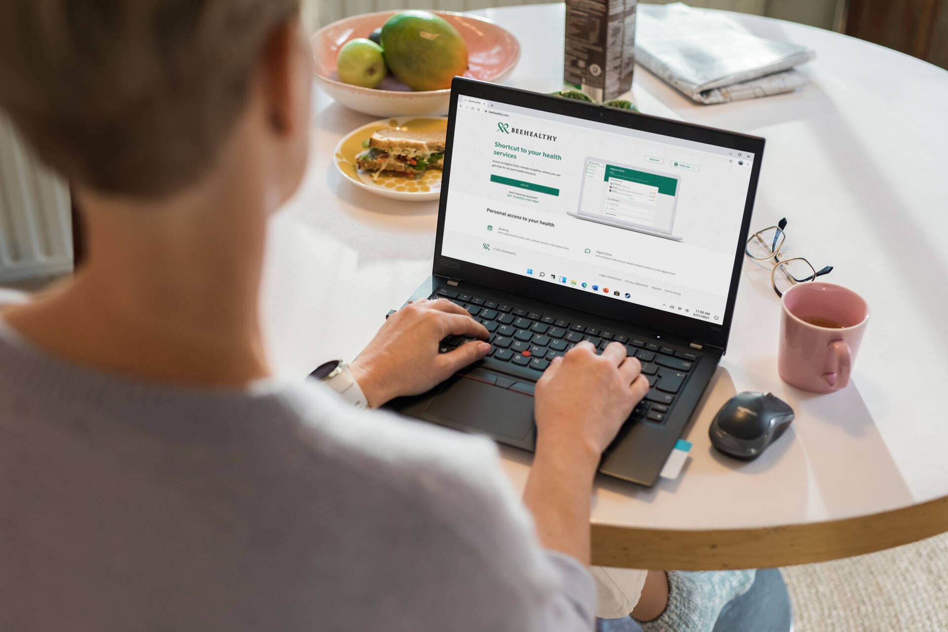 Henkilö istuu ruokapöydän äärellä ja selaa kannettavalla tietokoneella BeeHealthyn verkkosivuja.