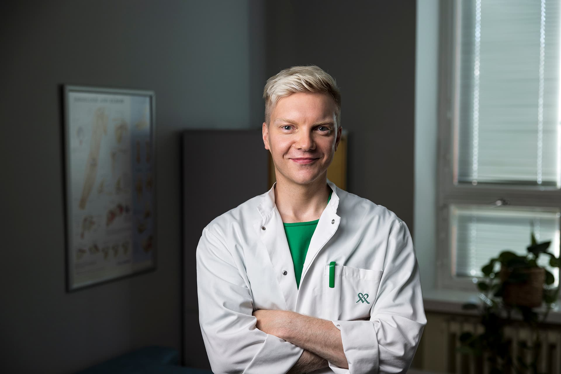 Mehiläisen lääkäri Niko hymyilee lääkärintakki päällään vastaanottohuoneessa.