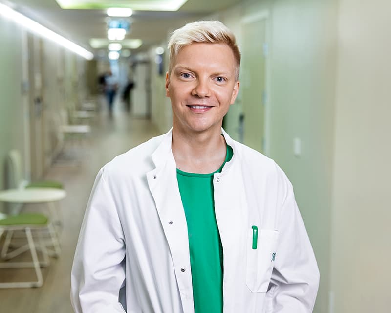 Mehiläisen lääkäri Niko seisoo käytävällä vastaanottohuoneen edessä.