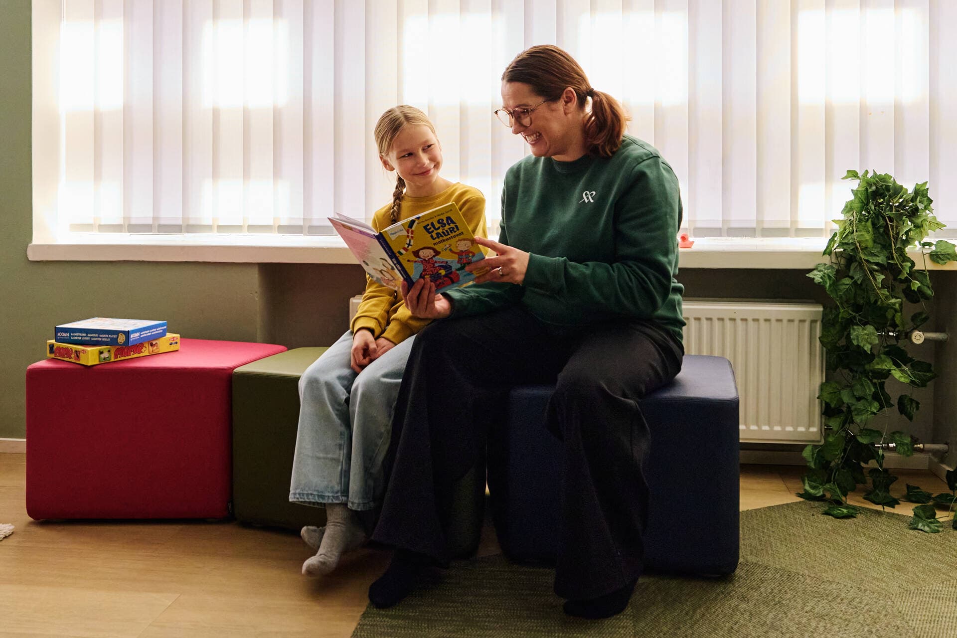 Puheterapeutti lukee kirjaa yhdessä lapsiasiakkaan kanssa.
