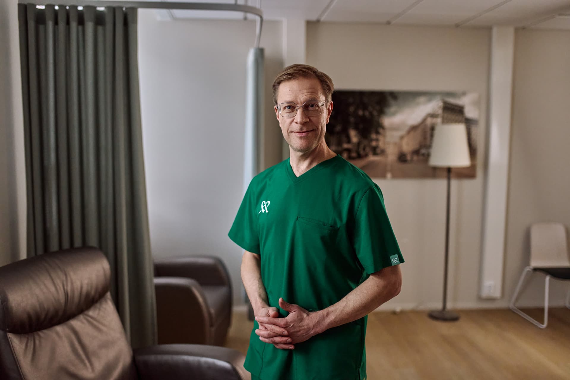 Mehiläisen ortopedi seisoo vastaanottotilassa ja katsoo kameraan hymyillen