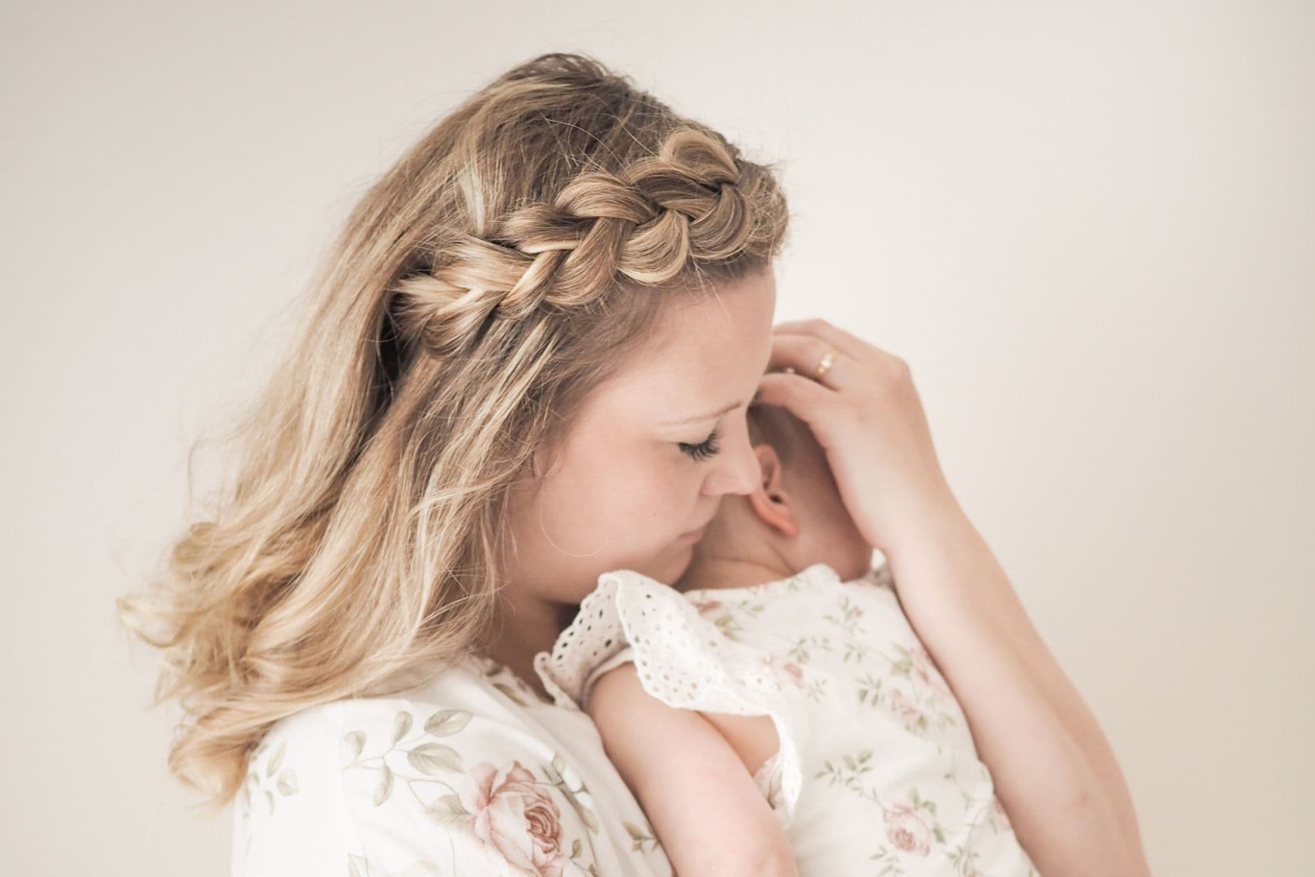 A woman holds a newborn baby on her shoulder.
