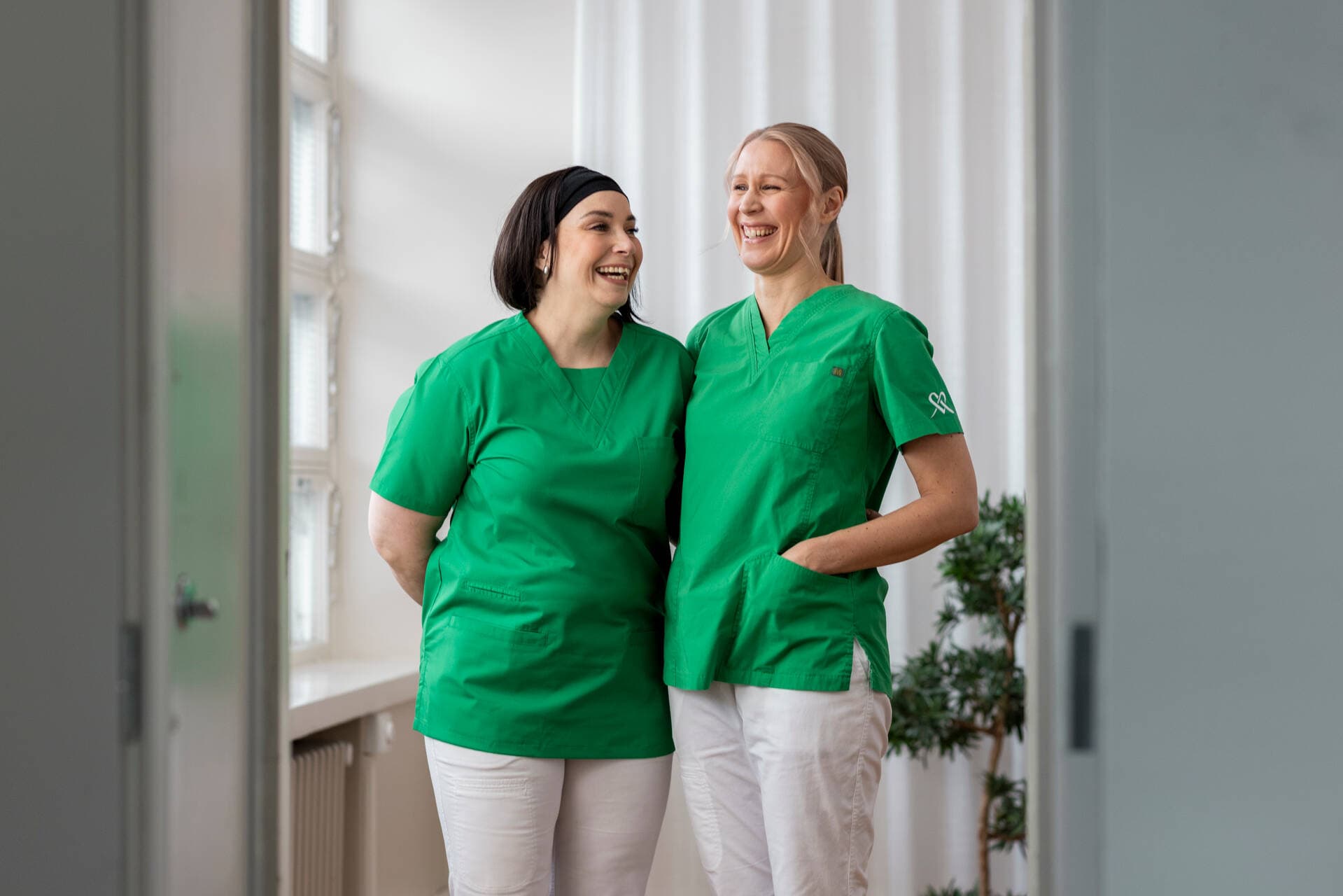 Two Mehiläinen nurses are smiling at each other.