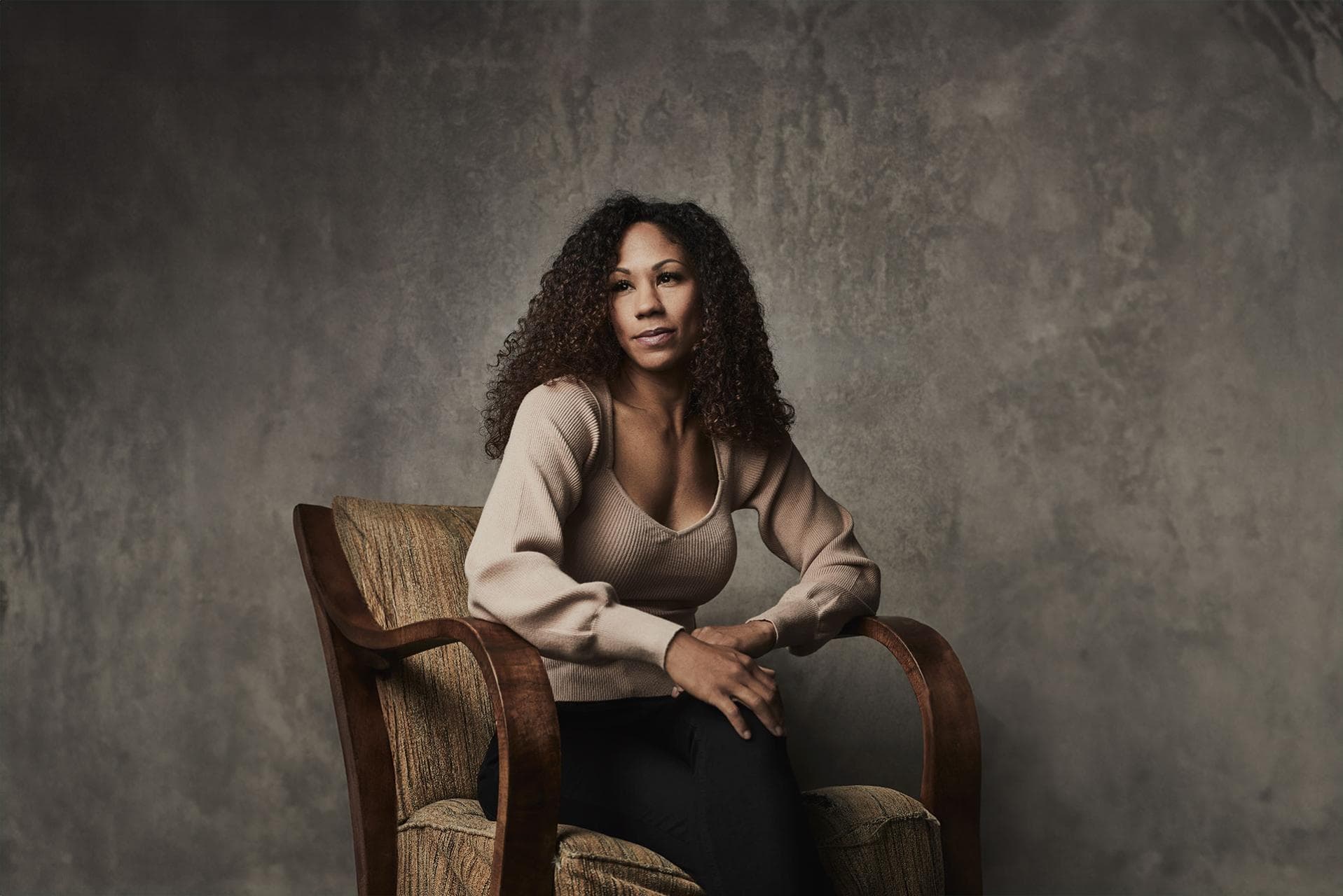 A young woman sits casually on a chair.