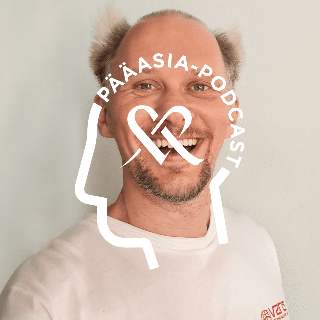 Jarno Laasala poserar för kameran i en närbild. På bilden finns en Pääasia Podcast-logo, där texten är formad som ett människohuvud och i mitten av logon finns Mehiläinens hjärta.