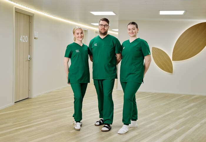 Tre anställda på Mehiläinen står bredvid varandra och ler