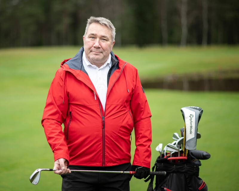 Mies punainen takki päällä seisomassa golfkentällä onnistuneesta selkäleikkauksesta toipuneena.