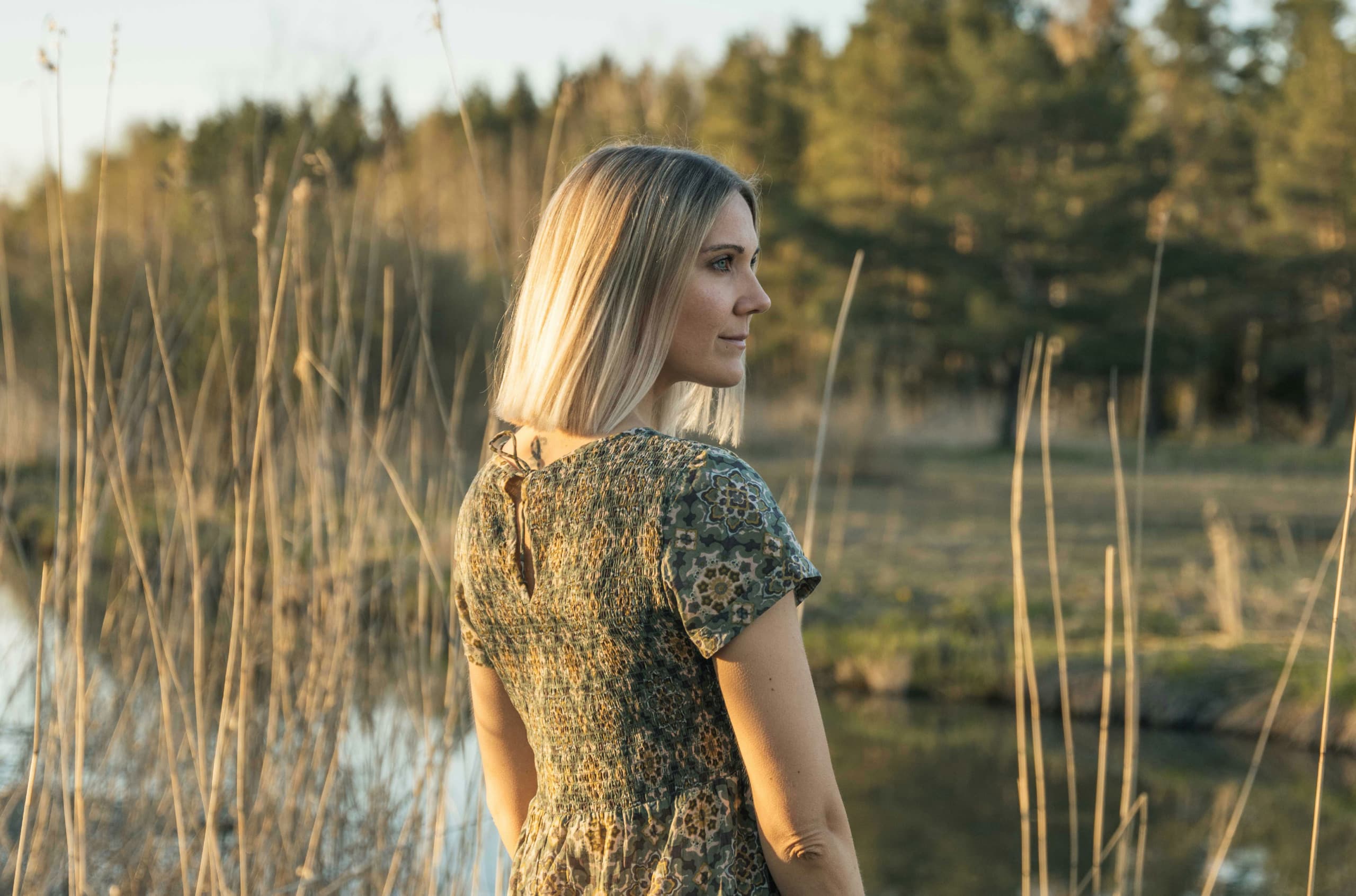 Johanna veden äärellä, selkä kameraa kohti, katsoo oikealle