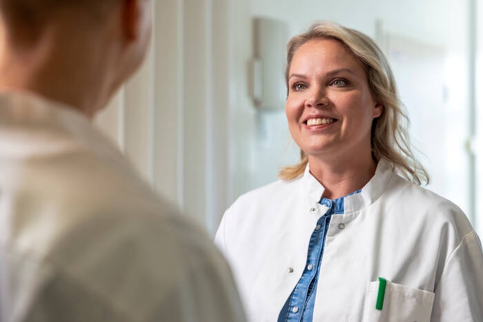 Mehiläinen's female physician smiles at the customer.