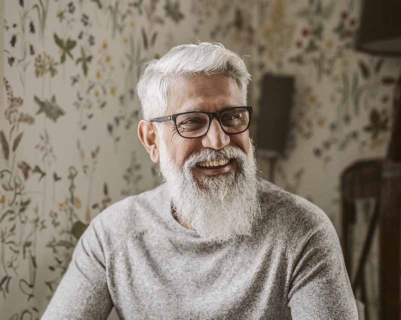 Keski-ikäinen mies istuu iloisena keittiönpöydän äärellä.