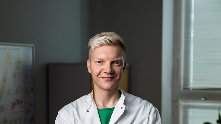 Mehiläisen yleislääkäri Niko hymyilee kameralle vastaanottohuoneessa.