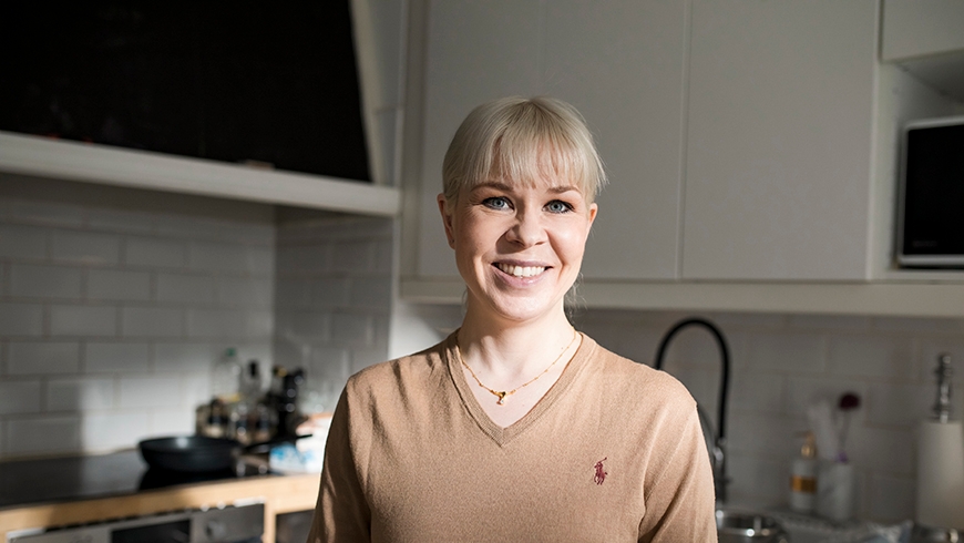 Mehiläisen iloinen vakuutusasiakas hymyilee keittiössä kameralle.