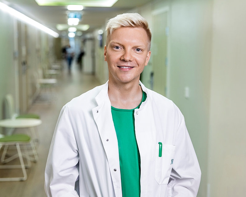 Mehiläisen lääkäri Niko seisoo käytävällä vastaanottohuoneen edessä.