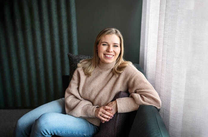 Lähetekoordinaattori istuu nojatuolilla ja hymyilee kameralle.