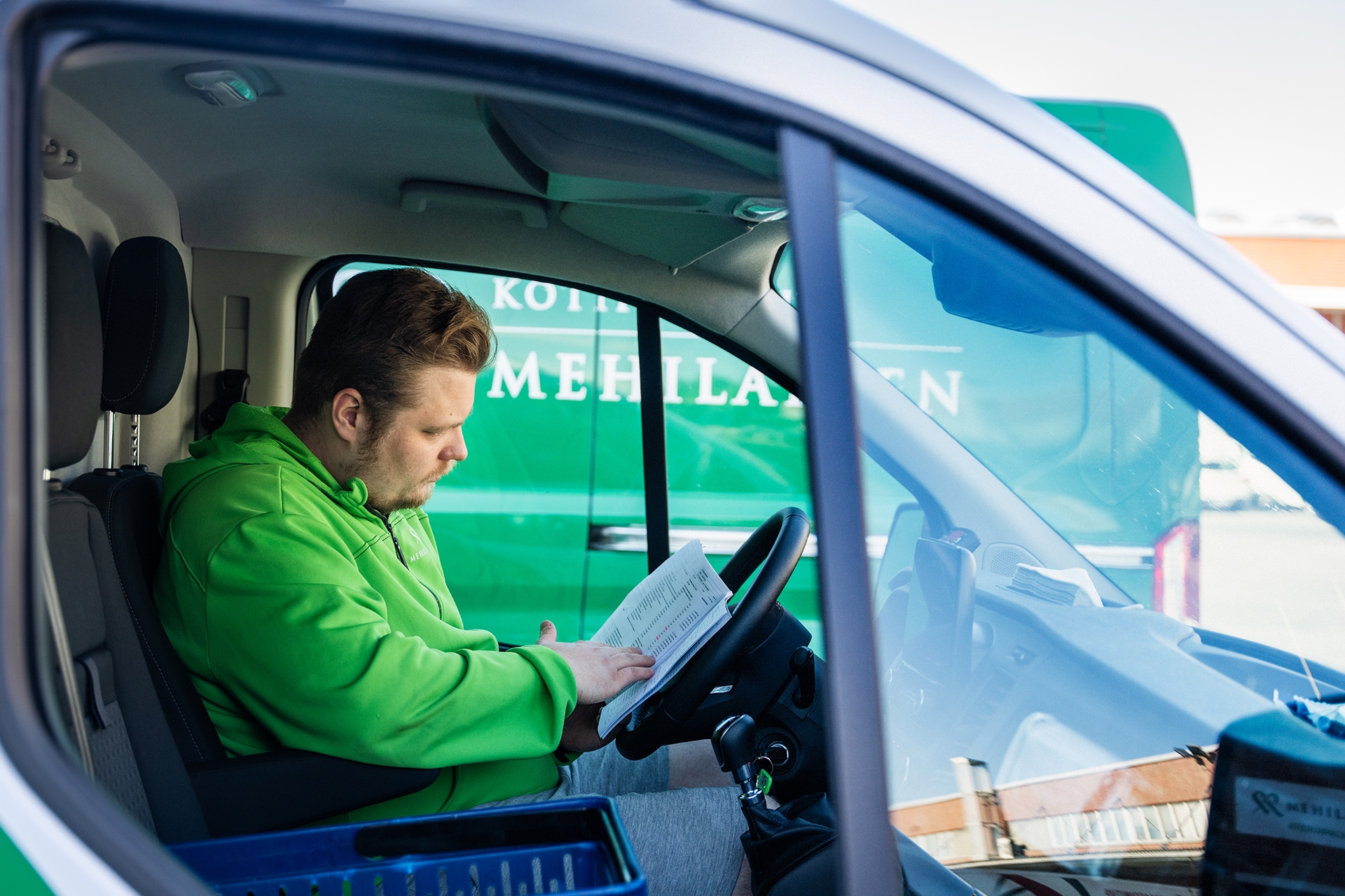 Mehiläisen ateriapalveluiden Anton tarkastamassa päivän tilauslistaa autossa.